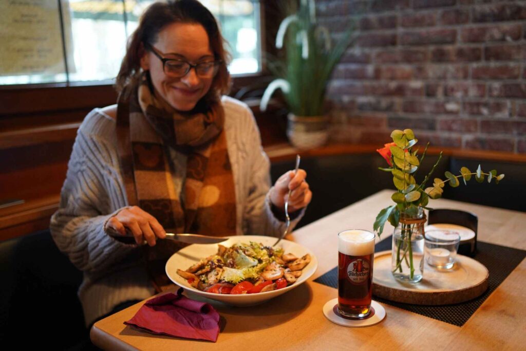 Fuchsbau Baumberg Restaurant Frau am Tisch mit Hähnchensalat