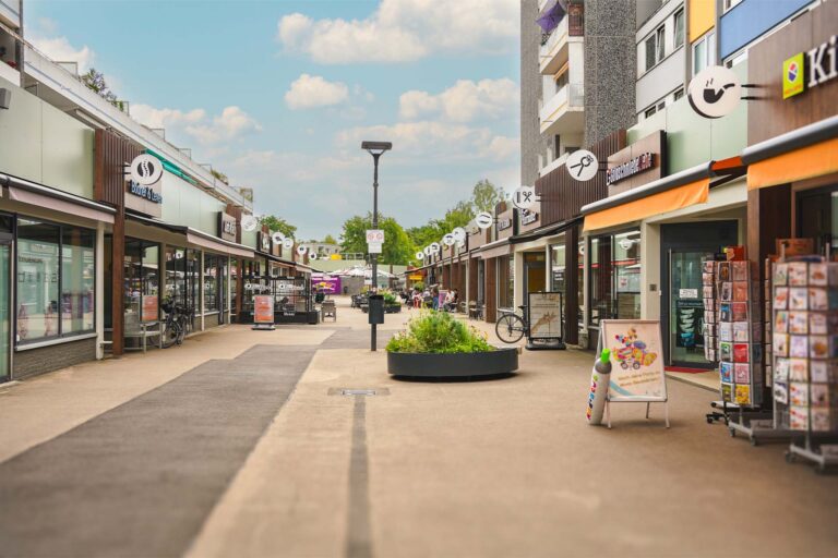 Fußgängerzone der Holzweg-Passage in Baumberg, Monheim mit Geschäften, Cafés und moderner Architektur.